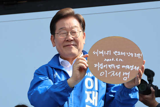 더불어민주당 이재명 대선 후보가 12일 경기 화성시 동탄 센트럴파크 음악분수중앙광장 유세장에서 '세계1위 반도체 강국 도약!'이라고 쓴 반도체 웨이퍼를 들어 보이고 있다. 연합뉴스