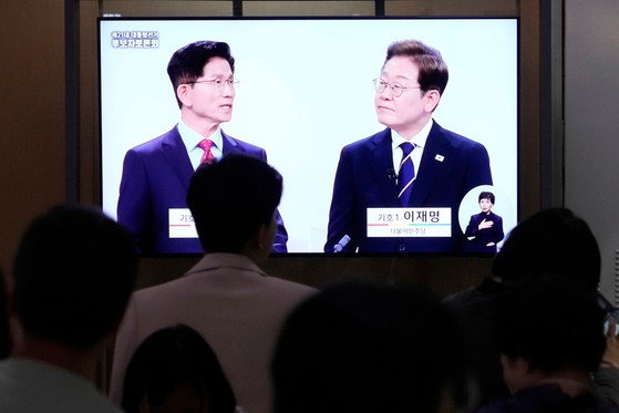 18일 서울역 대합실에서 시민들이 제21대 대통령선거 후보자 토론회 중계방송을 보고 있다. 이날 후보들은 경제를 주제로 토론을 펼쳤다. [AP=연합뉴스]