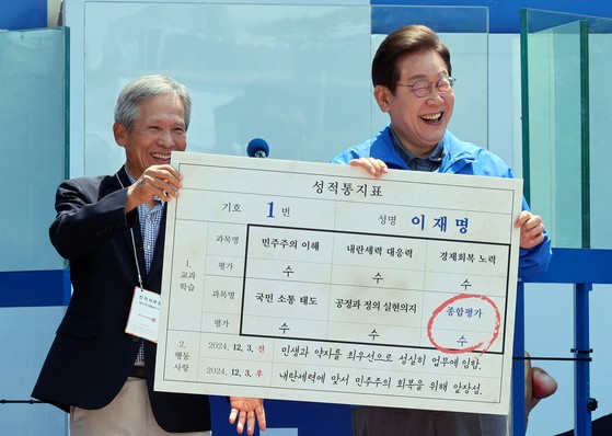 이재명 더불어민주당 대선 후보가 1일 오전 경북 안동시 웅부공원에서 유세 전 초등학교 은사인 박병기 씨로부터 성적표를 받고 있다. 김성룡 기자