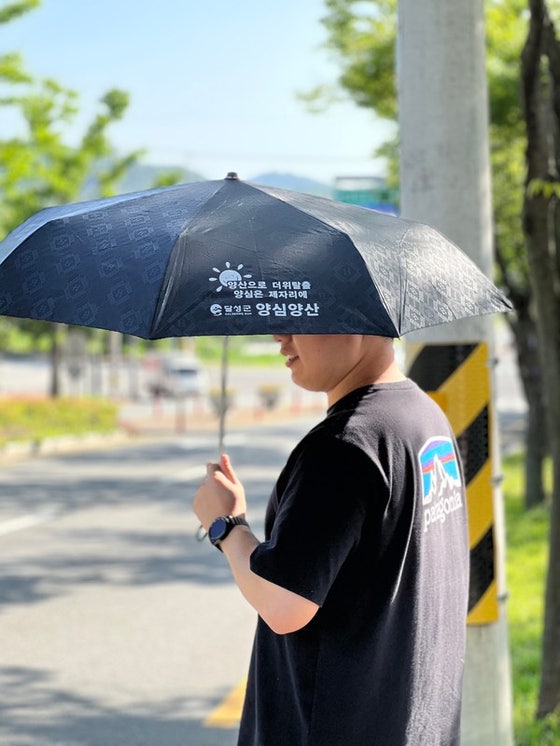 대구 달성군에서 한 시민이 뜨거운 햇살을 막기 위해 양심양산을 대여해 쓰고 있다. [대구 달성군]