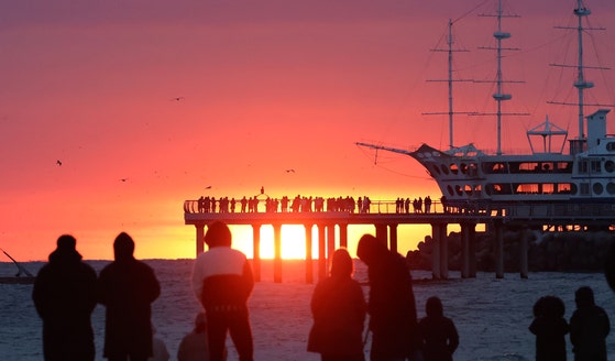 2026년 새해를 앞둔 지난 21일 해맞이 명소인 강원 강릉시 강동면 정동진 해변에서 관광객들이 해가 솟아오르는 장면을 바라보고 있다.[연합뉴스]