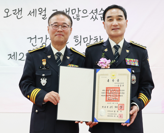 황창선 경기남부경찰청장이 지난해 12월 30일 경기 수원 장안구 경기남부경찰청에서 열린 빈준규(오른쪽) 총경,김병록 총경의 퇴임식에서 대리 수여한 녹조근정훈장증을 들고 기념 촬영하고 있다.사진 경기남부경찰청