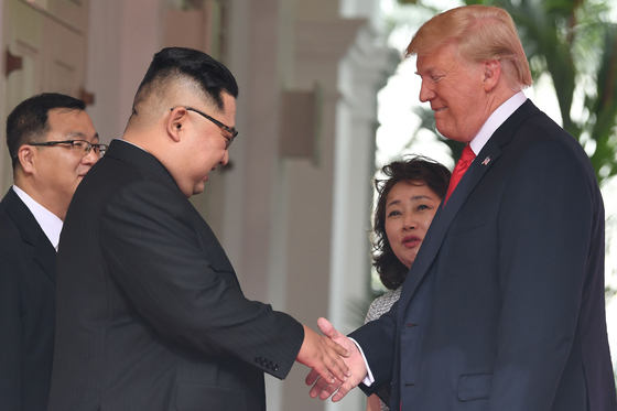 2018년 6월 12일 싱가포르 센토사섬 카펠라 호텔에서 열린 김정은 북한 국무위원장과 도널드 트럼프 미국 대통령 간 사상 첫 북ㆍ미정상회담에서 두 정상이 악수하는 모습을 북측 통역사 김주성,미국 측 이연향 통역관