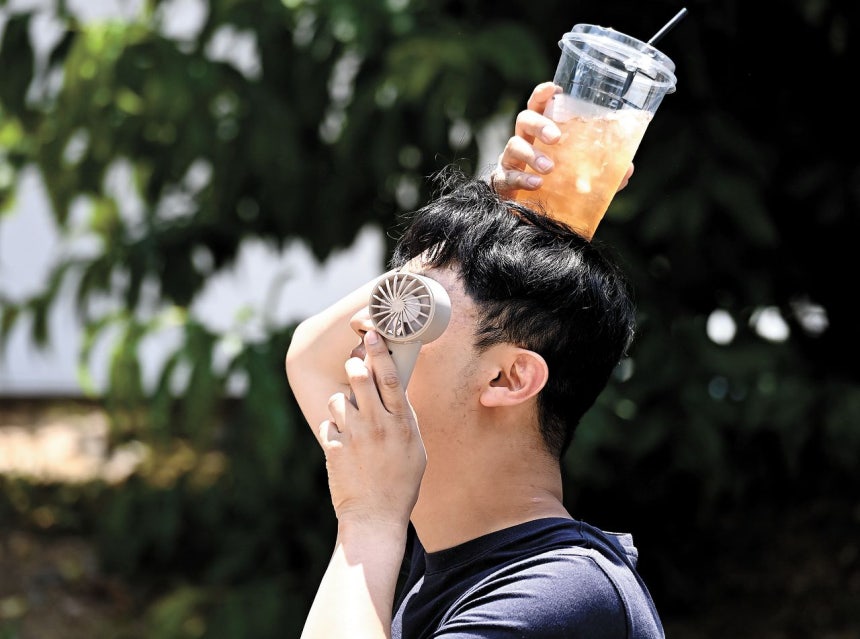 지난 17일 경기 수원시 팔달구 인계동에서 한 시민이 손선풍기와 얼음이 들어있는 음료컵을 머리에 올리며 더위를 식히고 있다.뉴시스