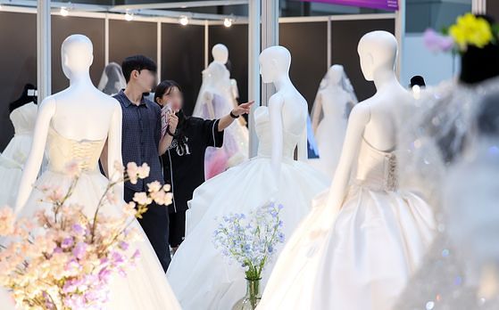 서울 강남구 삼성동 코엑스에서 열린 2025 추계 웨덱스 웨딩 박람회에서 예비 부부들이 전시된 드레스를 살펴보고 있다. 뉴스1