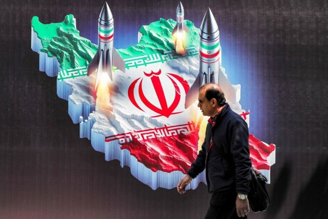 15일(현지시각) 이란 수도 테헤란에서 미사일 발사 모습을 상징적으로 표현한 이란 지도 그림 앞을 한 남자가 지나가고 있다. 2024-04-15 테헤란/AFP 연합뉴스