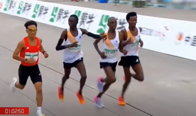 14일 중국 베이징에서 열린 하프 마라톤 대회에서 목표 지점을 1분 정도 앞두고, 에티오피아 선수가 중국 선수 허제(왼쪽)를 바라보며 방향을 가리키는 듯한 자세를 취하고 있다. 웨이보 갈무리