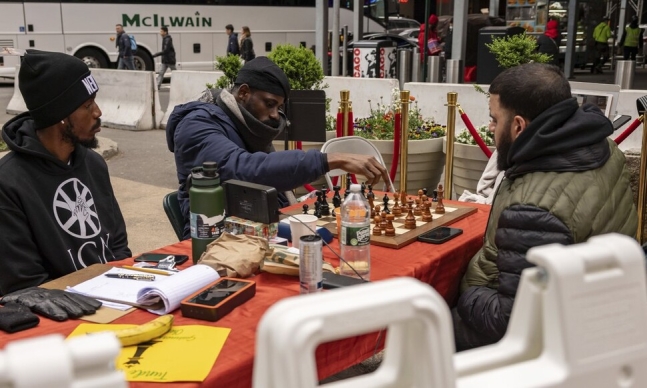 나이지리아 체스 선수 툰데 오나코야(가운데)가 19일(현지시각) 미국 뉴욕 타임스스퀘어에서 숀 마르티네스(오른쪽)와 체스 경기를 하고 있다. AP 연합뉴스