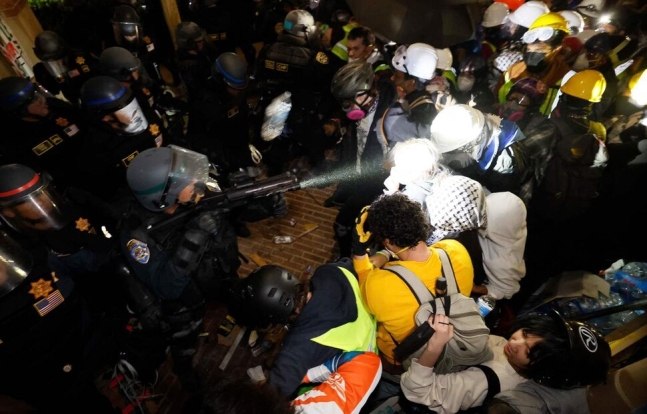 2일(현지시각) 미국 로스앤젤레스 캘리포니아대(UCLA)에서 경찰이 대치 중인 학생들을 향해 액체를 뿌리고 있다. AFP 연합뉴스