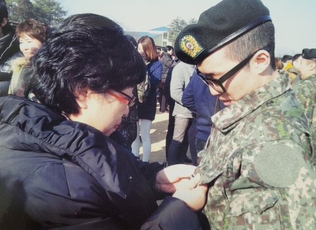 2015년 1월15일 육군28사단 훈련소 퇴소식 때 안미자씨(왼쪽)가 아들 승주씨의 군복에 이병 계급장을 달아주고 있다. 유족 제공