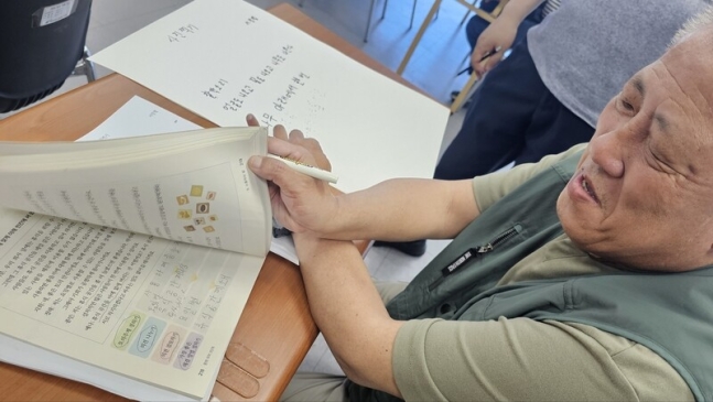 지난 23일 오전 대구 동구 질라라비장애인야학 5층 중3 교실에서 국어 수업 중인 서정협씨가 교과서를 보여주고 있다. 김규현 기자