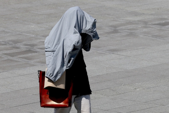 뜨거운 초여름 날씨가 이어진 29일 서울 광화문 광장에서 한 시민이 외투로 햇볕을 막으며 걸어가고 있다. 연합뉴스