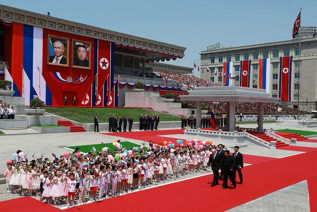 북한을 방문한 블라디미르 푸틴 러시아 대통령과 김정은 북한 국무위원장이 19일 낮 평양 김일성광장에서 열린 환영식에서 양국 국기를 흔드는 어린이들 앞을 지나가고 있다. 평양/로이터 연합뉴스