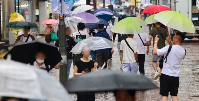 비가 내린 22일 오전 서울 명동거리에 시민들과 관광객들이 우산을 쓰고 이동하고 있다. 연합뉴스