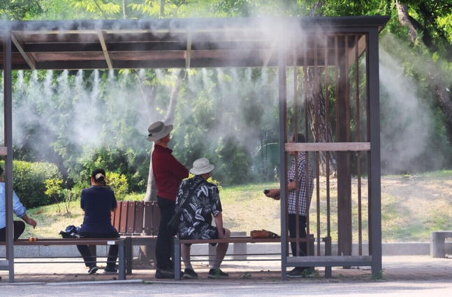 무더위가 기승을 부린 19일 서울 여의도공원에 설치된 쿨링포그 아래에서 시민들이 더위를 피하고 있다. 연합뉴스