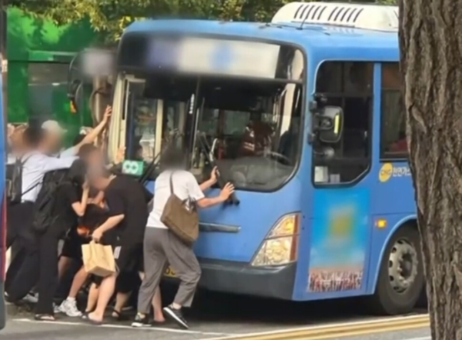 11일 서울 홍제역 인근 버스정류장에서 70대 여성이 버스에 깔리는 사고가 벌어지자, 시민들이 버스를 들어올려 여성을 구조하고 있다. 엠비엔 보도화면 갈무리