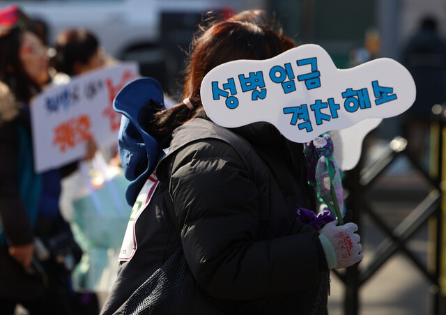 지난 3월8일, 전국민주노동조합총연맹이 개최한 ‘세계 여성의 날 정신 계승 전국노동자대회’에서 한 참가자가 ‘성별 임금 격차 해소’라고 적힌 손팻말을 들고 거리 행진을 하고 있다. 연합뉴스