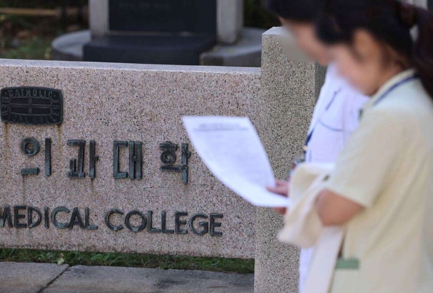 의대생들의 휴학을 대학이 자율적으로 승인할 수 있게 되면서 내년 의대 예과 1학년 학생 수가 최대 7500명에 이를 것으로 예상되는 가운데 30일 서울 시내 한 의과대학 앞으로 의료진이 지나가고 있다. 연합뉴스