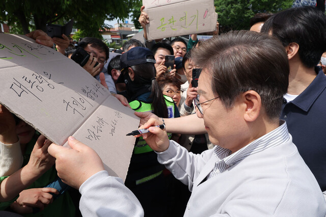 이재명 더불어민주당 대통령 후보가 ‘골목골목 경청투어: 국토종주편’에 나선 7일 전북 전주시 풍남문 앞 광장에서 지지자들에게 인사를 하던 도중 한 지지자가 든 ‘공판 연기 환영, 대통령은 국민이 뽑습니다’라는 팻말에