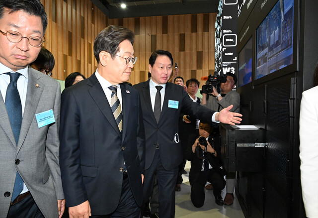 이재명 대통령이 20일 울산전시컨벤션센터에서 열린 인공지능(AI) 글로벌 협력 기업 간담회를 마친 뒤 AI 제품·서비스 시연을 참관하며 최태원 SK그룹 회장의 설명을 듣고 있다. 대통령실사진기자단