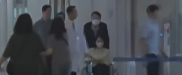 윤석열 전 대통령이 27일 오후 서울 송파구 서울아산병원에서 퇴원하는 김건희 여사의 휠체어를 밀고 있다. 와이티엔(YTN) 유튜브 영상 갈무리