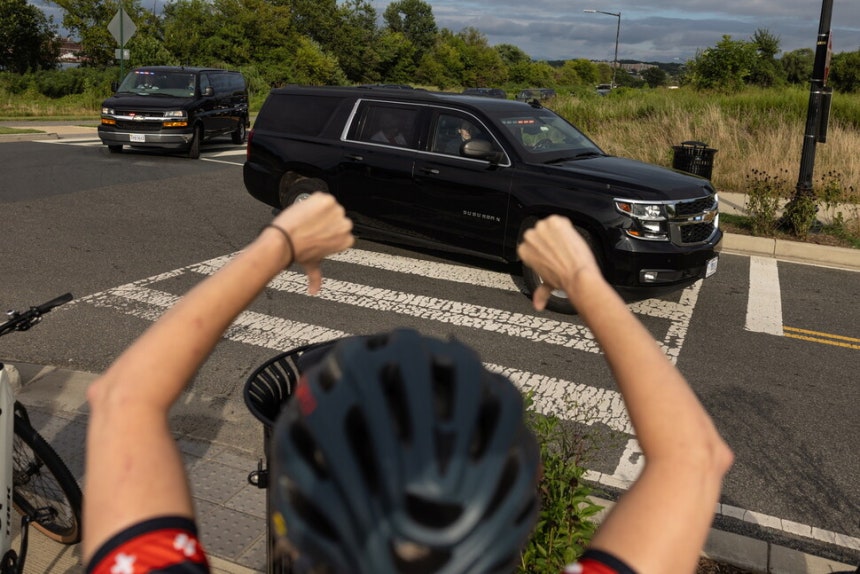 자전거를 탄 한 시민이 21일(현지시각) 미국 공원 경찰 본부에서 연설을 한 뒤 떠나는 도널드 트럼프 미국 대통령의 차량 행렬을 향해 항의하는 손짓을 하고 있다. 워싱턴/EPA 연합뉴스