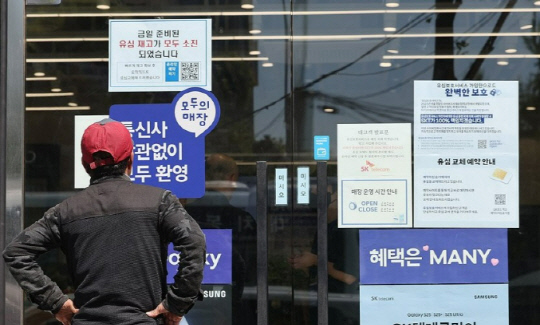2일 서울 시내의 한 SK텔레콤 대리점 앞에서 한 소비자가 유심 재고 소진 및 유심보호서비스 관련 안내문을 살펴보고 있다.연합뉴스 