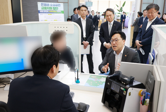 김병환 금융위원장이 8일 서울 중구 신한은행 본점에서 관계자로부터 소상공인 지원 프로그램에 대한 설명을 듣고 있다.뒷줄 왼쪽부터 이재연 서민금융진흥원장,<a href=