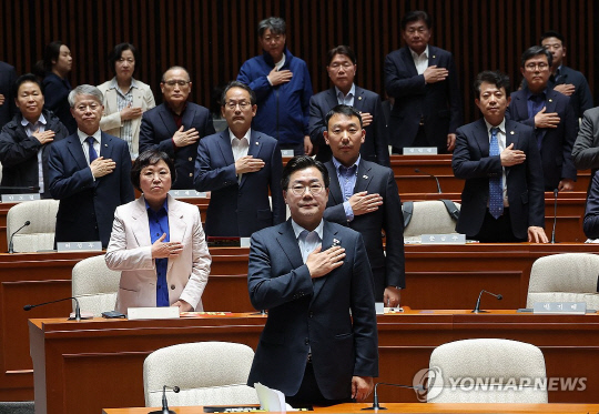 박찬대 더불어민주당 원내대표를 비롯한 의원들이 지난달 4일 국회에서 열린 긴급 의원총회에서 국기에 경례를 하고 있다. 연합뉴스