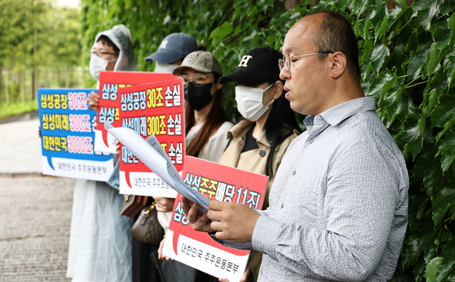 21일 서울 용산구 이재용 삼성전자 회장 자택 앞에서 열린 삼성전자 주주 총결집 집회에서 삼성전자 주주단체인 ‘대한민국 주주운동본부’ 관계자들이 손팻말을 들고 있다.  [연합뉴스]