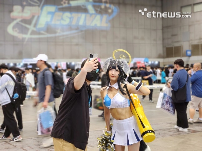 A player dressed as a costume player of the Blue Archive game character and a user participating in the 2.5th anniversary festival are taking a commemorative photo.
