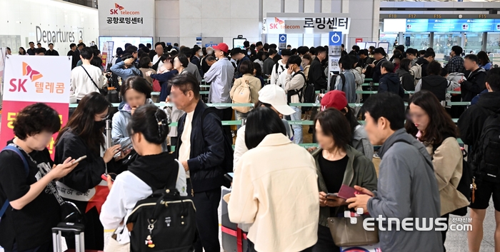 6일 간의 황금연휴가 시작된 1일 인천국제공항 1터미널 출국장에서 SK텔레콤을 이용하는 여행객들이 유심 교체를 위해 줄지어 서 있다.인천국제공항공사는 6일까지 공항 이용객이 약 148만 명에 달할 것으로 예상되며,