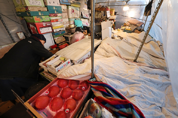 한파 속 서울 송파구 가락농수산물종합도매시장의 한 점포에서 상인이 과일을 이불로 덮고 있다.[사진=연합뉴스]