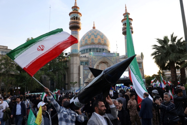 이란 수도 테헤란에서 15일(현지시간) 열린 이란 혁명수비대의 이스라엘 본토 공격 기념행사에서 한 참가자가 미사일 모형을 들고 있다. 로이터연합뉴스