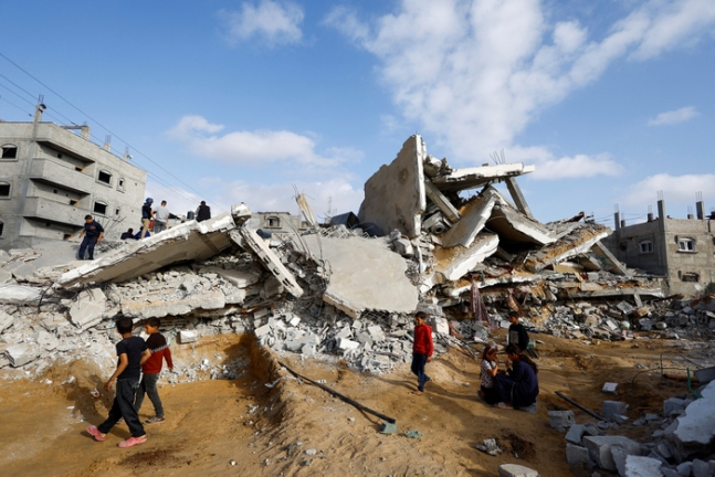 팔레스타인 어린이들이 21일(현지시간) 가자지구 남부 라파에서 이스라엘군의 공습으로 붕괴한 건물 앞을 지나가고 있다. 로이터연합뉴스