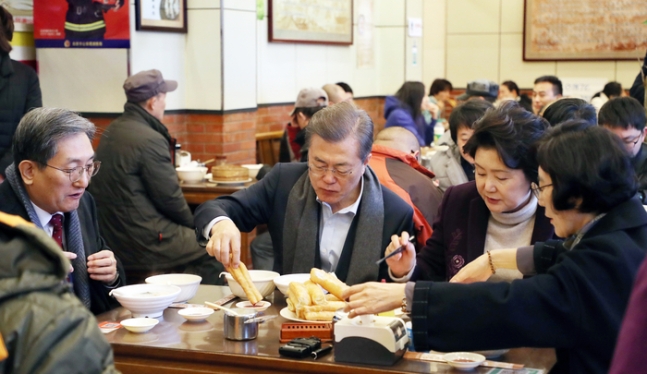 문재인 전 대통령과 부인 김정숙 여사가 2017년 12월 14일 오전 중국 베이징 조어대 인근 한 현지 식당에서 중국인들이 즐겨 먹는 아침 메뉴 중 하나인 유탸오와 더우장으로 식사를 하고 있다. 이후 해당 장면은 ‘