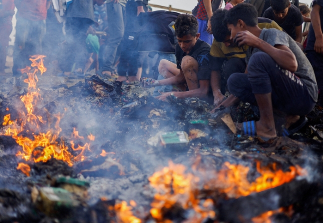 이스라엘군이 ‘안전지대’로 지정했던 가자지구 라파 북서쪽 탈 알술탄 난민촌을 공습한 다음날인 27일(현지시간) 피란민들이 불탄 잔해 속에서 식량을 찾고 있다. 로이터연합뉴스