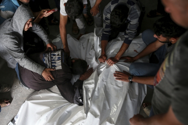 27일(현지시간) 가자지구 최남단 도시 라파의 한 영안실에서 주민들이 전날 이스라엘군의 공습으로 사망한 희생자들의 가족을 안고 애도하고 있다. AP연합뉴스