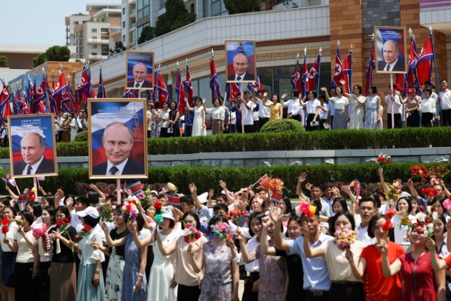 19일 평양 시내에서 북한 주민들이 푸틴 대통령을 태운 차량을 향해 환영의 인사를 하고 있다. 스푸트니크·AP = 연합뉴스