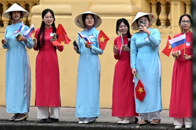 베트남 전통의상 아오자이를 입은 여성들이 20일(현지시간) 베트남 하노이 주석궁 앞에서 블라디미르 푸틴 러시아 대통령의 도착을 기다리고 있다. AFP연합뉴스