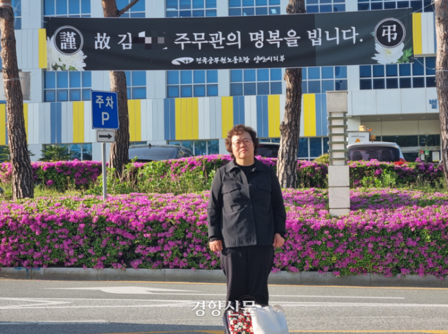 김수진씨(가명)의 어머니 송명옥씨(가명)가 지난 4월 진영씨가 일했던 경남 양산시청 앞에 걸린 추모 현수막을 등지고 서 있다. 강한들 기자