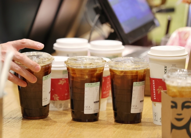 서울 강남구의 한 스타벅스에서 시민이 구입한 커피를 집어들고 있다. 연합뉴스