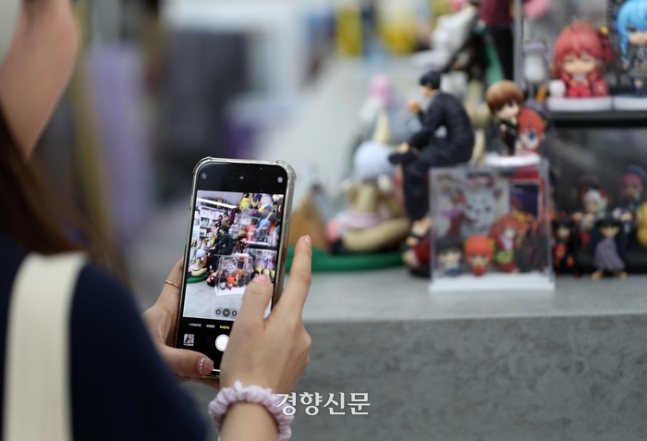 한 시민이 지난달 26일 서울 마포구 홍대 거리 피규어 가게에 진열된 각종 제품들을 휴대전화로 촬영하고 있다. 이른바 ‘홍키하바라’는 홍대입구역 4번 출구 바로 앞 AK플라자에서 합정역으로 가는 방향 500m 골목 