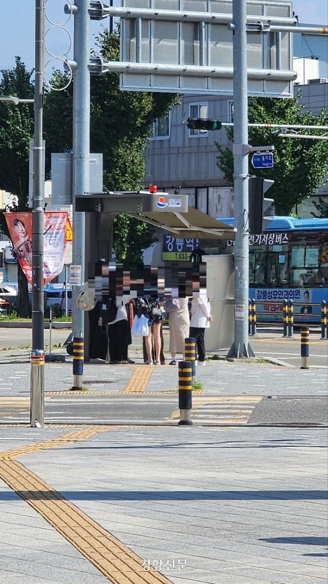 지난 10일 강원 강릉시 강릉역 앞 횡단보도에서 관광객들이 좁은 스마트그늘막의 그늘 안에서 뙤약볕을 피하고 있다. 김기범 기자