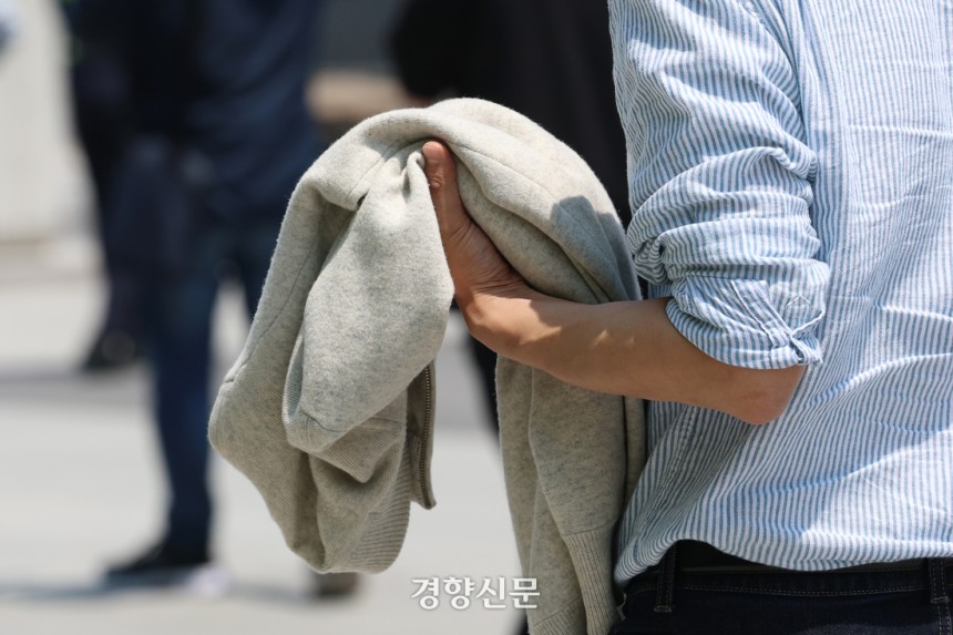 서울의 낮 최고 기온이 24도까지 오르며 초여름 날씨를 보인 지난 12일 서울 광화문 광장을 찾은 시민이 겉옷을 벗어든 채 걷고 있다. 정효진 기자