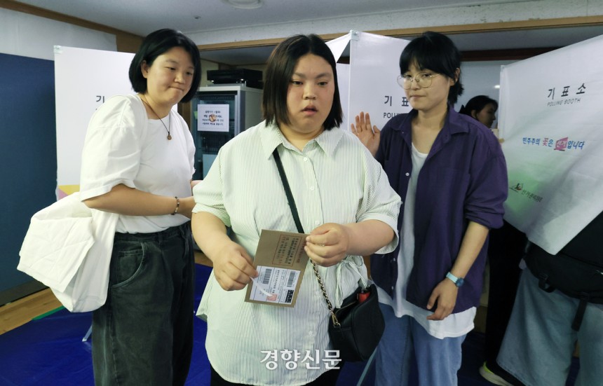 발달장애인 박경인씨(가운데)가 지난 29일 서울 종로구보건소에 마련된 청운효자동 사전투표소에서 동행 활동가들의 도움을 받아 투표를 하고 있다. 서성일 선임기자