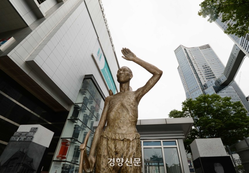 시민들이 2017년 8월13일 서울 용산역 광장에 설치된 ‘강제징용 노동자상’을 바라보며 지나고 있다. 동상은 강제징용 노동자가 한 손에 곡괭이를 들고 다른 한 손으로 햇빛을 가리는 모습으로 고된 노동의 고통을, 오