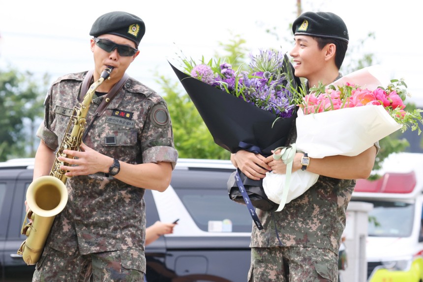 그룹 방탄소년단(BTS)의 RM과 뷔가 10일 강원 춘천시 신북읍체육공원 축구장에서 전역 인사를 하고 있다. 군악대에서 복무한 RM은 색소폰 연주를 하고 있다. 연합뉴스