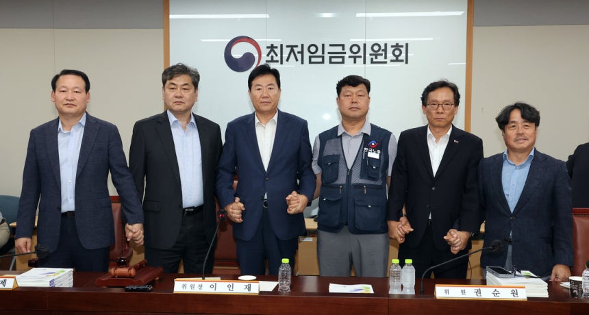 10일 정부세종청사에서 열린 제12차 전원회의에서 내년 최저임금을 시간당 1만320원으로 17년 만에 합의로 결정한 공익위원·사용자위원·근로자위원들이 손을 잡고 기념촬영을 하고 있다. 연합뉴스