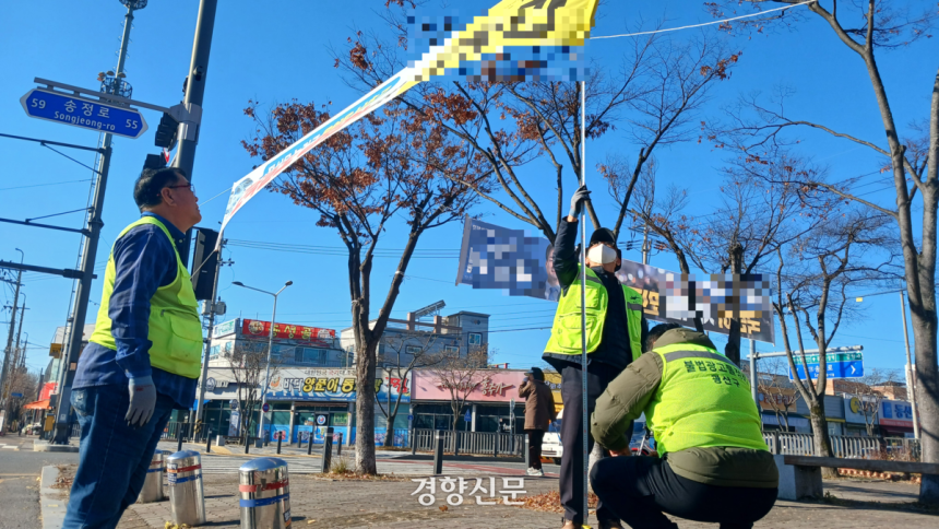 3일 광주 광산구의 한 교차로에서 광산구 불법광고물 정비원들이 교통섬에 게시된 정당 현수막의 높이를 줄자를 이용해 재고 있다.강현석 기자.